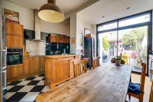 une grande cuisine avec une table en bois et une grande fenêtre dans l'établissement Charmante chambre en dépendance, à Bordeaux