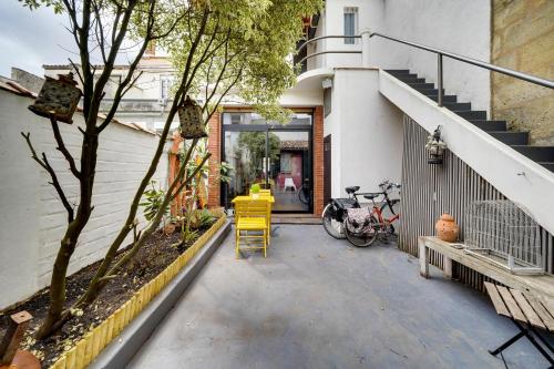 une terrasse avec une chaise jaune en face d'un bâtiment dans l'établissement Charmante chambre en dépendance, à Bordeaux