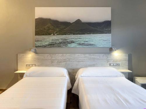 two beds in a room with a picture on the wall at Te Maná Hotel in Torreblanca