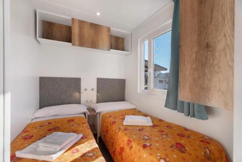 a bedroom with two beds and a window at Dkamping Village in Ispra