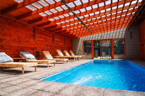 an indoor swimming pool with chairs and a wooden ceiling at Cabañas hualle sur cerca huilo huilo in Panguipulli