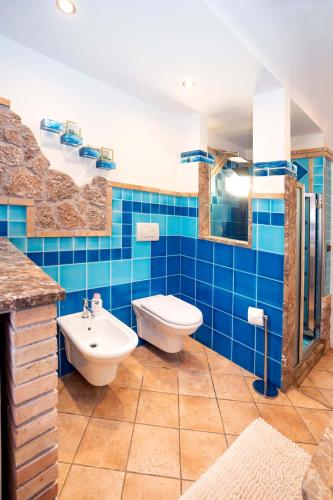 a blue tiled bathroom with a toilet and a sink at Appartamento Letojanni-Taormina in Letojanni