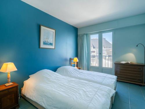 una camera da letto blu con un letto e una finestra di La Trinité-sur-Mer : Appartement 3 pièces avec parking, proche port et plages - FR-1-477-180 a La Trinité-sur-Mer