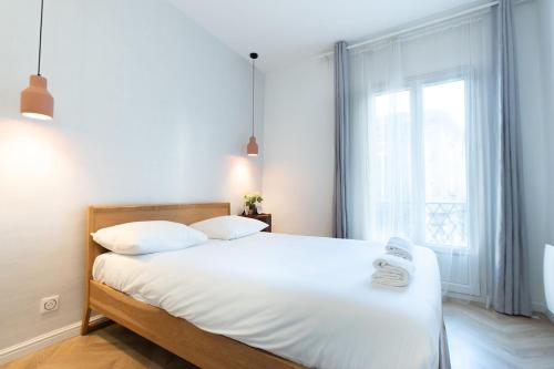 une chambre avec un grand lit blanc avec une fenêtre dans l'établissement L'Harmonieux Beau T3 centre ville, à Montpellier