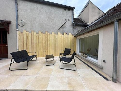 un patio avec quatre chaises et une clôture en bois dans l'établissement Maison Familiale - Proche Fontainebleau Paris, à Champagne-sur-Seine