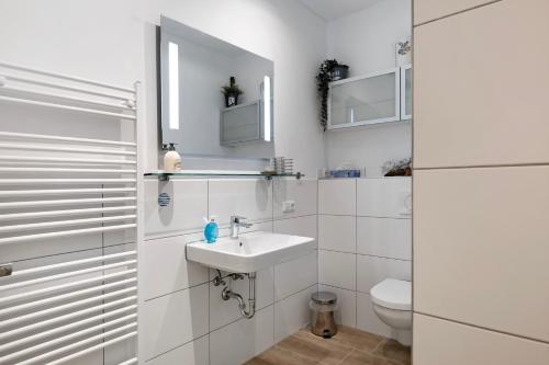 a white bathroom with a sink and a toilet at Tu Huus in Wesselburen