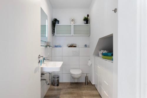 a white bathroom with a sink and a toilet at Tu Huus in Wesselburen