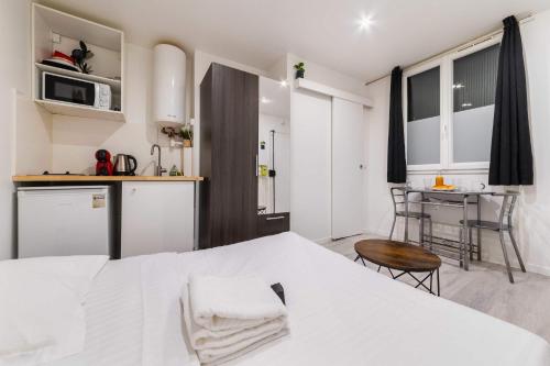 a bedroom with a white bed and a kitchen at Studio fonctionnel hopital bichat - paris 18 - 2P in Paris