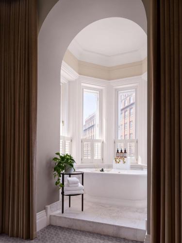 a bathroom with a bath tub and a window at Kimpton Fitzroy London by IHG in London
