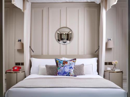 a bedroom with a large bed and a mirror at Kimpton Fitzroy London by IHG in London