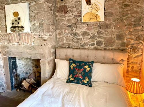a bedroom with a bed with a stone wall at Cheviot House Gallery And Guest Rooms in Wooler