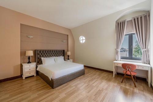 a bedroom with a bed and a desk and two windows at Villa La Rose Blanc Thảo Điền in Ho Chi Minh City