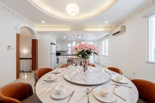 a dining room with a table with a vase of flowers at Villa La Rose Blanc Thảo Điền in Ho Chi Minh City