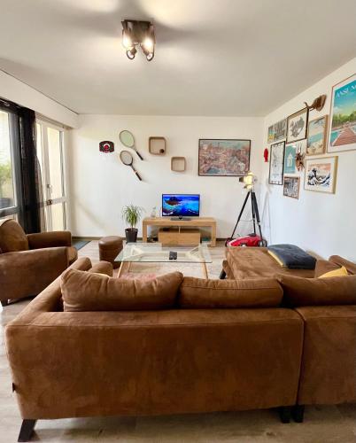 una sala de estar con 2 sofás marrones y una mesa. en Le Belvédère - Bord de Sarthe - 4pers, en Le Mans