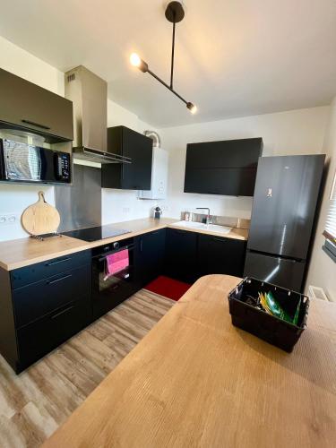 une cuisine avec des armoires noires et une table en bois dans l'établissement Le Belvédère - Bord de Sarthe - 4pers, au Mans