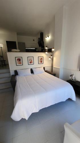 - une chambre dotée d'un grand lit blanc avec deux photos sur le mur dans l'établissement Cap d'Antibes Duplex studio Garden-terrace Beaches, à Antibes