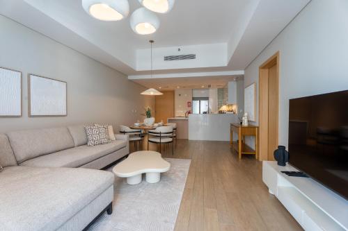 a living room with a couch and a tv and a table at Sustainable Stylish Mayan 1 Bedroom - Yas Island 809 Mayan 4 in Abu Dhabi