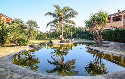 a garden with a pond with palm trees and a building at Lovely Apartment In Puntone Di Scarlino in Puntone di Scarlino
