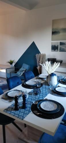 une table avec des chaises bleues et des assiettes dessus dans l'établissement Maison de Charme, proche Paris, Maison Laffitte, gare Sartrouville, à Sartrouville