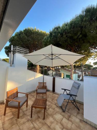 a patio with a table and two chairs and an umbrella at Villetta Onda Blu in Punta Marina