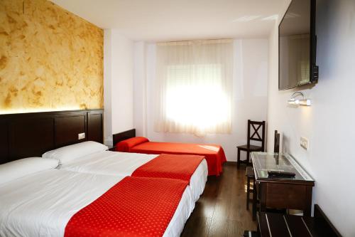 a hotel room with two beds and a window at Hotel Restaurante Sostenible La Laguna in Brozas