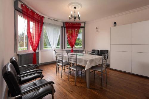 - une salle à manger avec une table, des chaises et des rideaux rouges dans l'établissement Maison confortable près de la Forêt de Brocéliande, BBQ, à La Chapelle-Caro