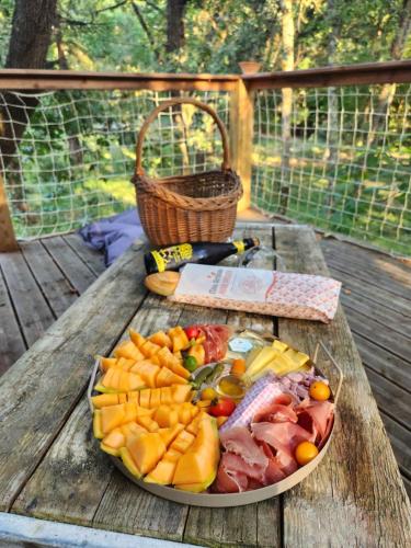 une assiette de fruits et légumes sur une table en bois dans l'établissement La cabane des bords d'Ariège, à Grépiac