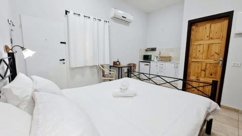 a white bedroom with a bed and a kitchen at חדרי נופש פסגת ההר in Rosh Pinna