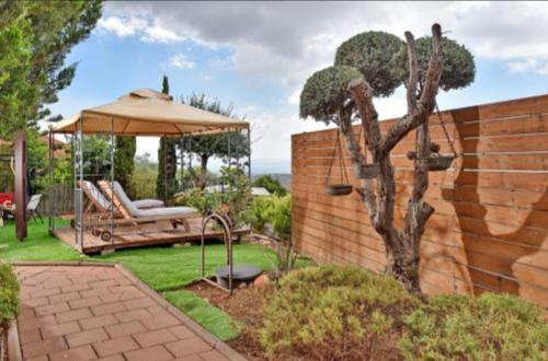 a garden with a gazebo and a tree at חדרי נופש פסגת ההר in Rosh Pinna