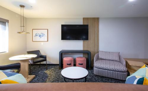 a hotel room with a couch and chairs and a tv at voco Flagstaff by IHG in Flagstaff