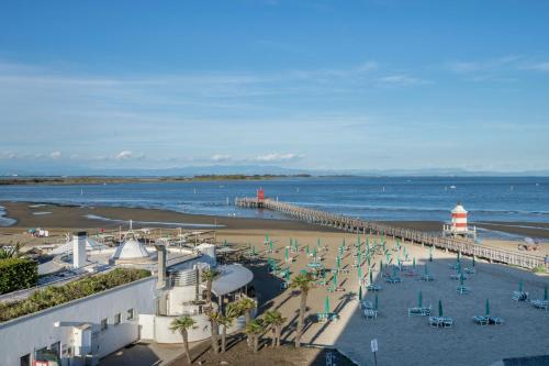 a beach with a pier and chairs and a lighthouse at La terrazza sul faro in Lignano Sabbiadoro