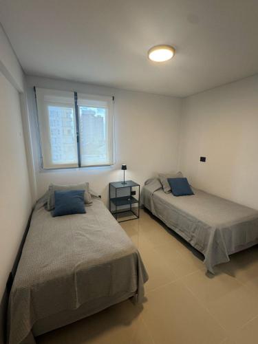 a bedroom with two beds and a table and two windows at Madryn al Mar in Puerto Madryn