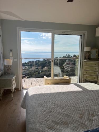 une chambre avec un lit et une grande fenêtre en verre dans l'établissement Vue époustouflante sur la mer, au Lavandou