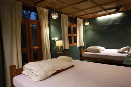two beds in a room with green walls and windows at Backpackers eco village in Japur