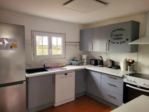 Elle comprend une petite cuisine avec des placards blancs et une fenêtre. dans l'établissement Gîte des Etourniaux, à La Poterie-Mathieu