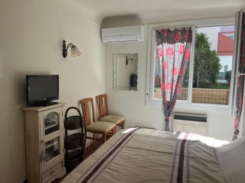 une chambre avec un lit, une télévision et une fenêtre dans l'établissement Hossegor Centre Ville T2 Rez de Chaussée Terrasse, à Hossegor