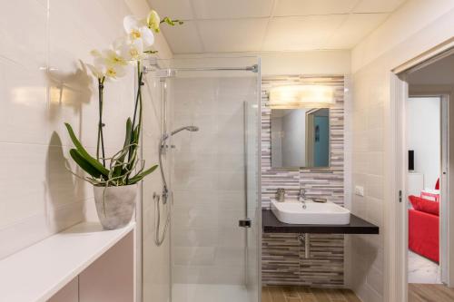 baño con ducha, lavabo y jarrón con flores en Residence Klima House de Vilos, en Arco