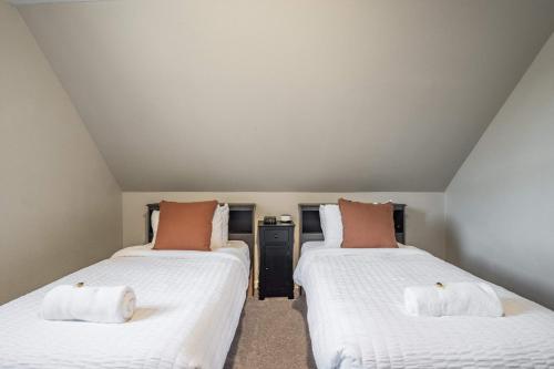 two beds in a room with white and orange pillows at Mountain Villa Scenic Views Hot Tub & Fire Pit in Cascade-Chipita Park