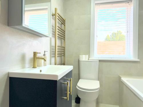 a bathroom with a sink and a toilet and a window at Entire Cosy Flat in Radlett - 3 Bedrooms -5 Beds - Sleeps 8 - Fast Train access into central London in Radlett