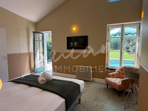 une chambre avec un lit, une chaise et des fenêtres dans l'établissement Villa Chocomaitea - Élégance et douceur de vivre, à Biarritz