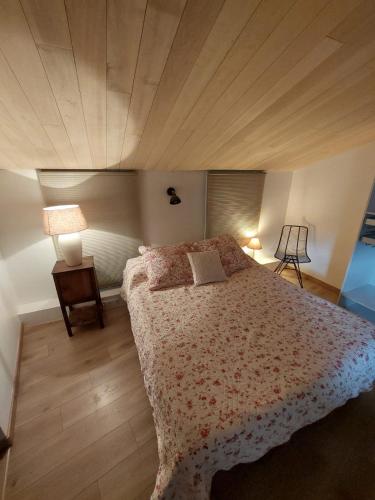une chambre avec un lit et un plafond en bois dans l'établissement Le Loft, à Bruniquel