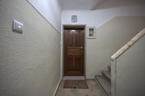 a hallway with a wooden door and a stairway at Jamor Terrace by Homing in Cruz Quebrada
