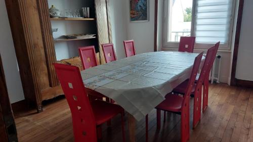 d'une table à manger entourée de chaises rouges. dans l'établissement Maison 5 min de la plage, à Quiberon