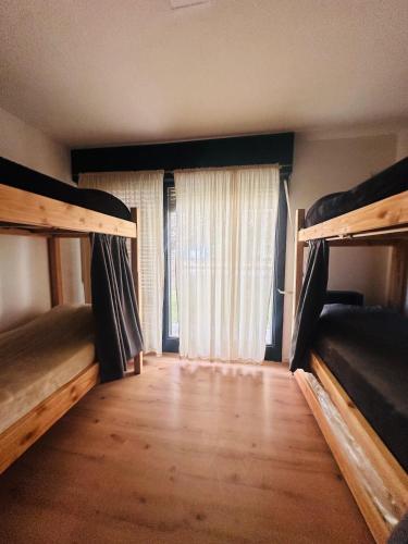 a room with two bunk beds and a window at Travesia Sur Hostel in El Bolsón
