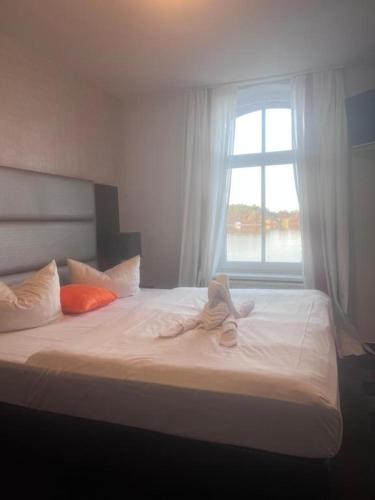 a bedroom with a white bed with a window at MiLANO Seehotel in Krakow am See