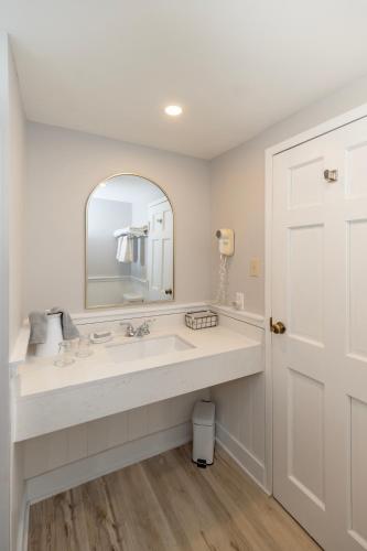 a white bathroom with a sink and a mirror at Brandywine River Hotel in Chadds Ford