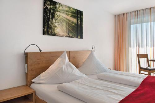 a bedroom with a bed with white sheets and a window at Gästehaus D i c k r e i t e r in Immenstaad am Bodensee