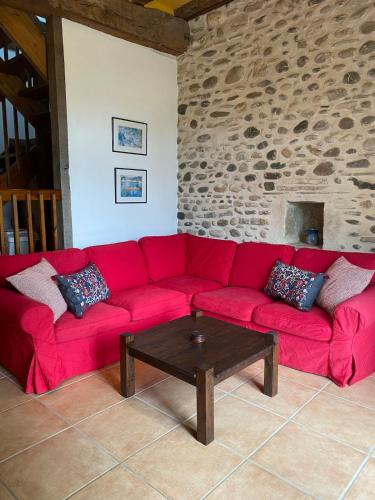 - un canapé rouge dans le salon avec une table dans l'établissement Les Galets - Converted barn near the Pyrenees, à Préchacq-Josbaig