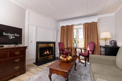 a living room with a couch and a table and a fireplace at Brandywine River Hotel in Chadds Ford