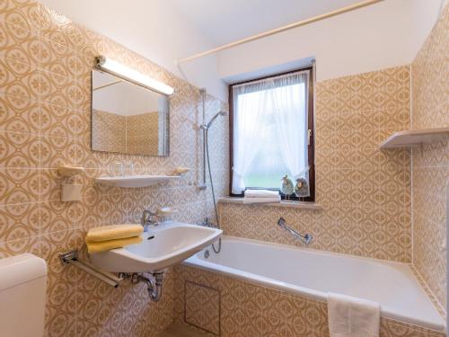 ein Badezimmer mit Waschbecken, Badewanne und Spiegel in der Unterkunft Ferienwohnanlage Oberaudorf E3 mit Hallenbad und Sauna in Oberaudorf